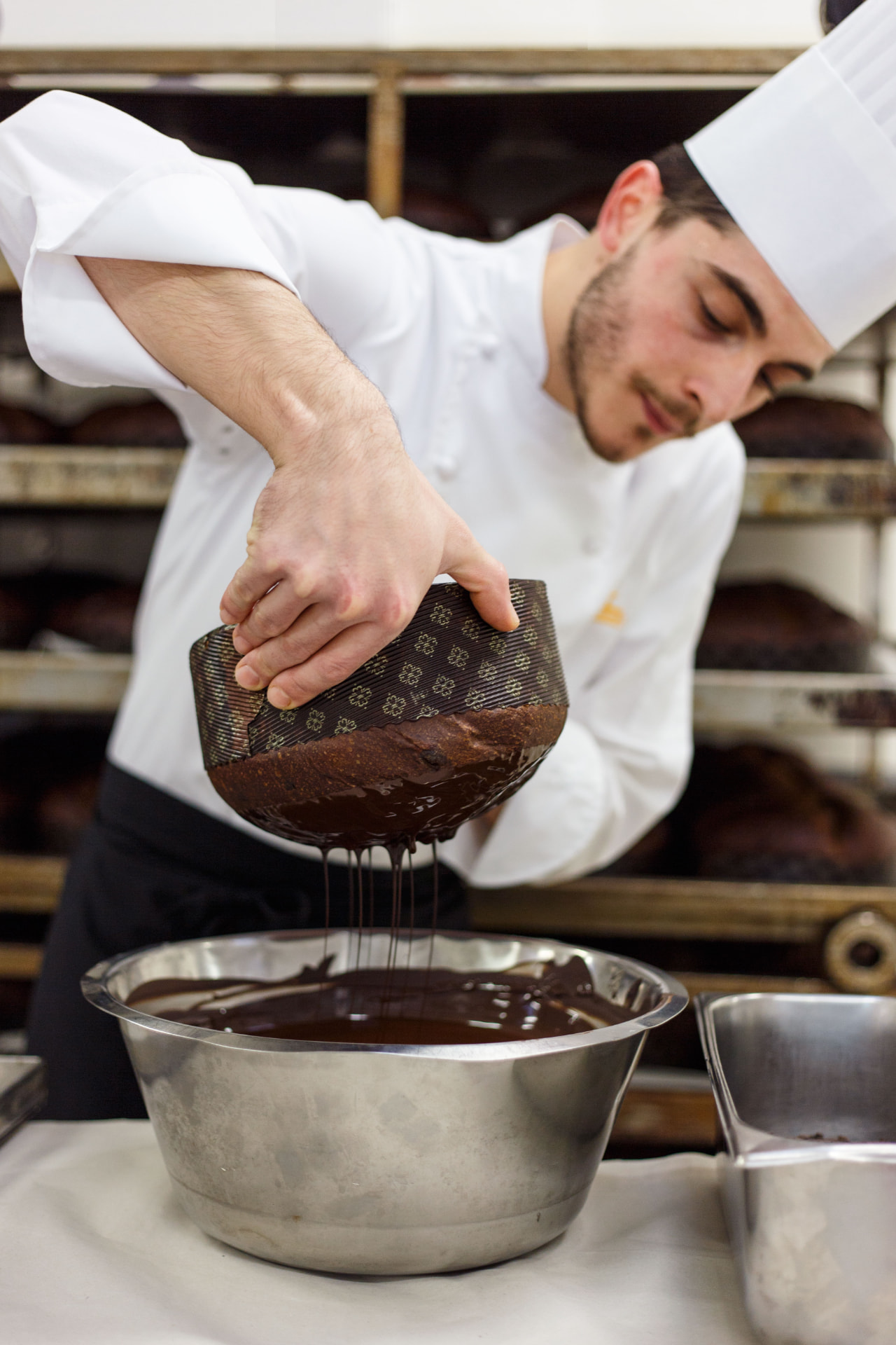 Konditor taucht einen handwerklich gebackenen italienischen Panettone in flüssige Schokolade